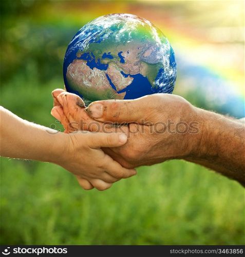 Senior man and baby holding the Earth in hands against a rainbow in spring. Ecology concept