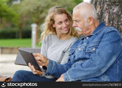 senior man and daughter using tablet outdoors