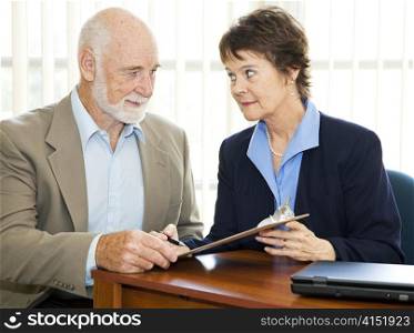 Senior man and his agent or broker having a serious discussion before he signs paperwork.