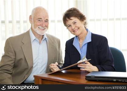 Senior man and mature businesswoman going over paperwork in the office.