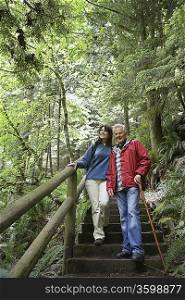 Senior man and middle-aged woman walking on forest trail