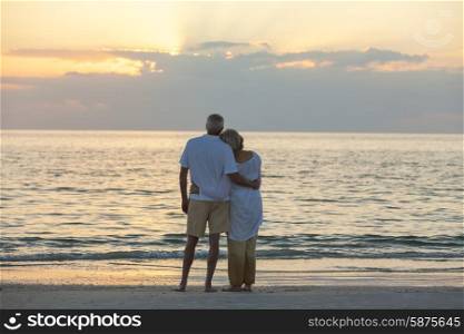 Senior man and woman couple embracing at sunset or sunrise on a deserted tropical beach