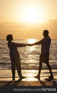 Senior man and woman couple holding hands at sunset or sunrise on a deserted tropical beach