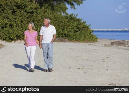 Senior man and woman couple holding hands walking on a deserted beach
