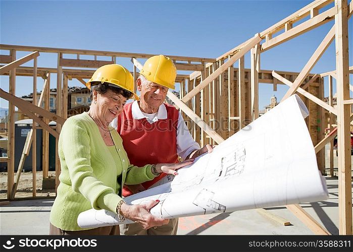 Senior man and woman examining blueprint in construction site
