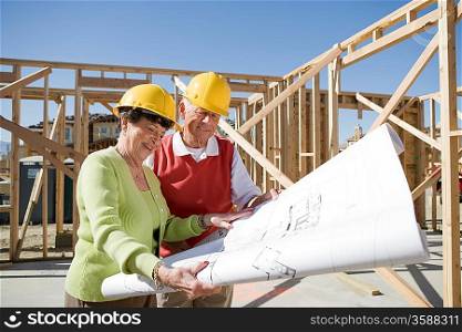 Senior man and woman examining blueprint in construction site