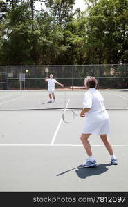 Senior man and woman playing in a tennis match.