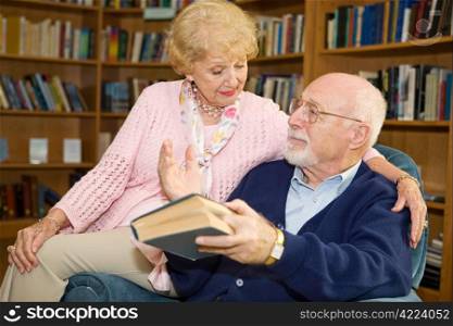 Senior man and woman reading together and discussing.
