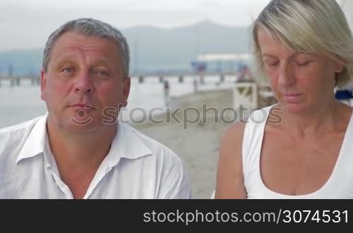 Senior man and woman sticking moustache to each other and making funny faces. Fun together
