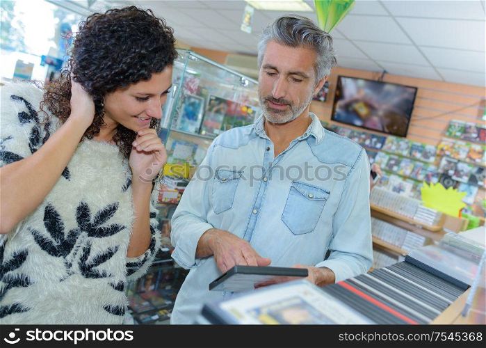 Senior man and young lady looking at DVDs