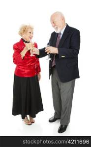 Senior man at a holiday party handing his beautiful wife a glass of champagne. Full body isolated on white.