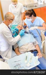 Senior man at dentist surgery having teeth checkup dental assistant