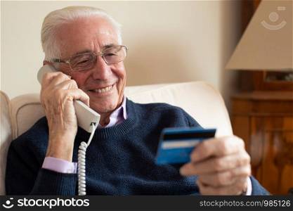 Senior Man At Home Giving Credit Card Details On The Phone