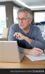 Senior man at home in front of laptop computer