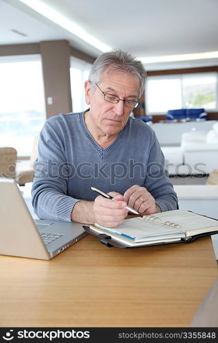 Senior man at home in front of laptop computer