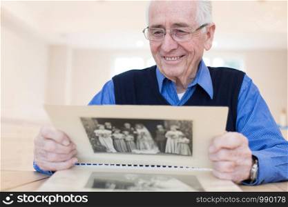 Senior Man At Home Looking At Photo Album