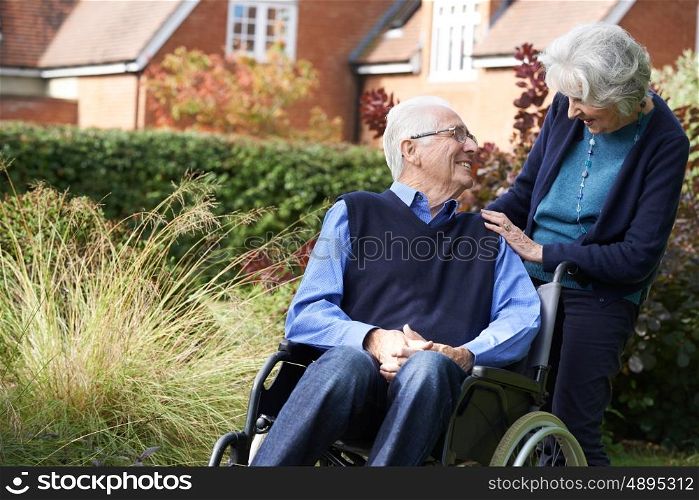 Senior Man Being Pushed In Wheelchair By Wife