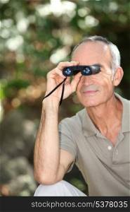 Senior man bird watching with binoculars