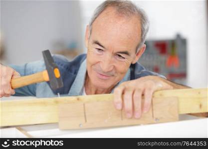 senior man carpenter working with hammer