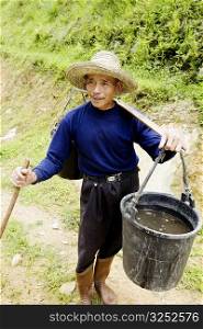 Senior man carrying a bucket full of water on his shoulder, Jinkeng Terraced Field, Guangxi Province, China