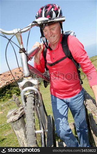 Senior man carrying mountain bike