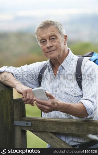 Senior Man Checking Location With Mobile Phone On Hike