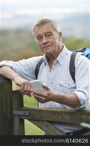 Senior Man Checking Location With Mobile Phone On Hike