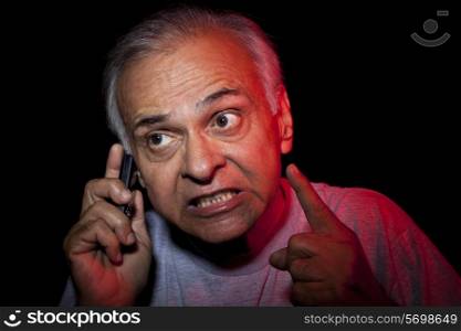 Senior man clenching teeth while having conversation on phone