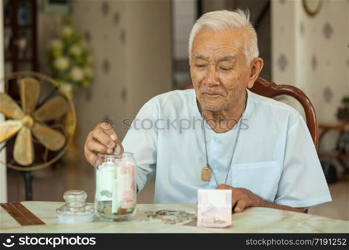 senior man counting money with glass bank