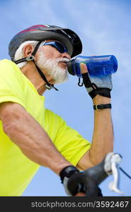 Senior man cycling and drinking water