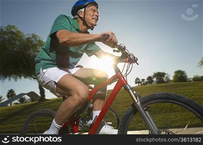 Senior man cycling in park at dusk
