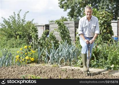 Senior Man Digging Vegetable Patch On Allotment