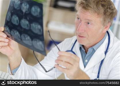 senior man doctor examines mri image in hospital
