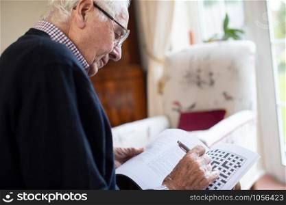 Senior Man Doing Crossword Puzzle At Home