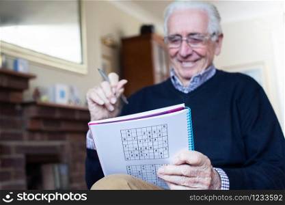 Senior Man Doing Sudoku Puzzle At Home