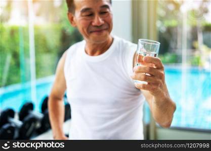 Senior man drink mineral water in gym fitness center after exercise. Elderly healthy lifestyle.. Senior man drink mineral water in fitness center.