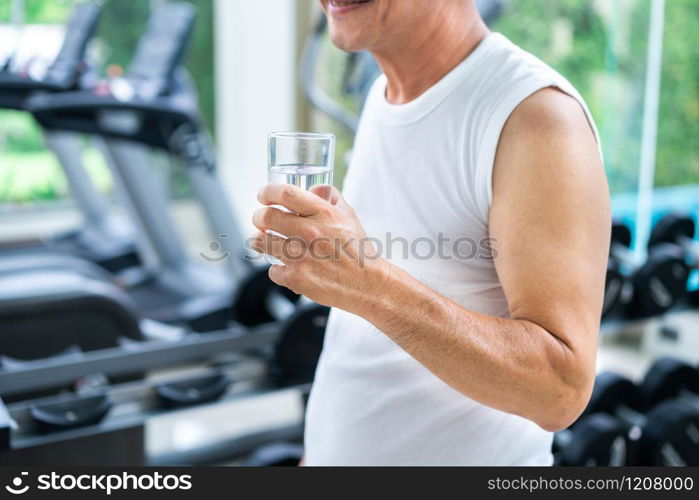 Senior man drink mineral water in gym fitness center after exercise. Elderly healthy lifestyle.. Senior man drink mineral water in fitness center.