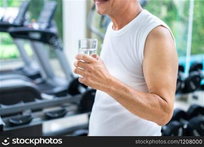 Senior man drink mineral water in gym fitness center after exercise. Elderly healthy lifestyle.. Senior man drink mineral water in fitness center.