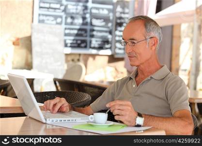 Senior man drinking coffee and checking his e-mails