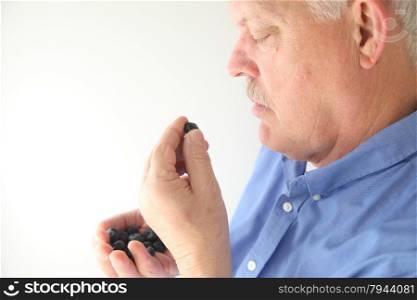 senior man eating blueberries out of hand
