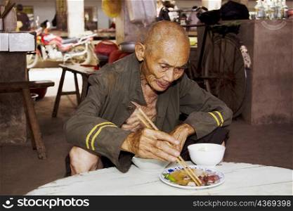Senior man eating food in a restaurant, Xingping, Yangshuo, Guangxi Province, China