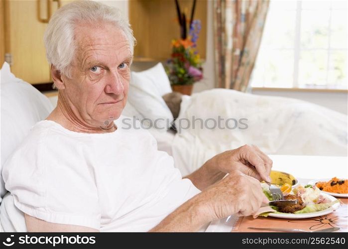Senior Man Eating Hospital Food In Bed