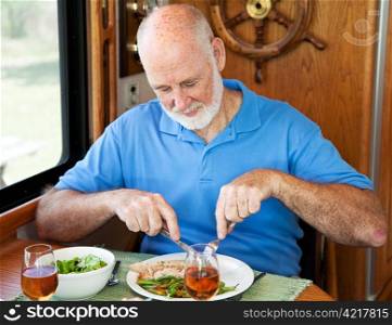 Senior man enjoys a healthy dinner of turkey, green beans and salad, in his motor home.