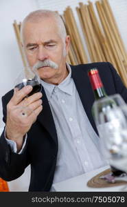 senior man examining glass of red wine