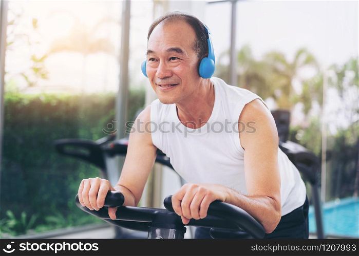 Senior man exercise on cycling machine in fitness center. Mature healthy lifestyle.