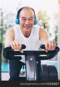 Senior man exercise on cycling machine in fitness center. Mature healthy lifestyle.