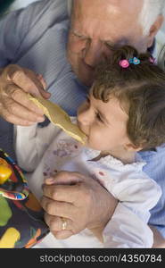 Senior man feeding papadam to her granddaughter