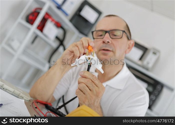 senior man fixing electric plug