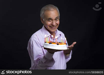 Senior man gesturing while holding cake