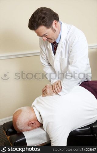 Senior man gets an adjustment to a friendly chiropractor.
